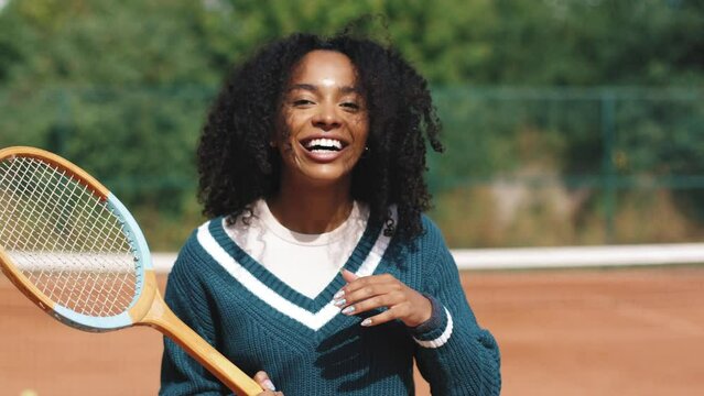 4k video. Young and beautiful sporty african american woman playing tennis in clay court. Amatour frienship match. Vintage and retro racket. Natural tree background.