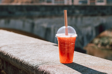 Glass of strawberry and mango bubble tea closeup on city background