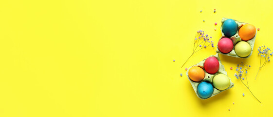 Cardboard holders with painted Easter eggs and flowers on yellow background with space for text