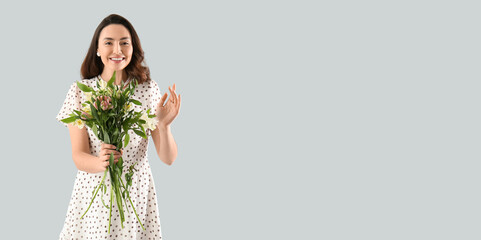 Beautiful happy young woman with bouquet of alstroemeria flowers on light background with space for...