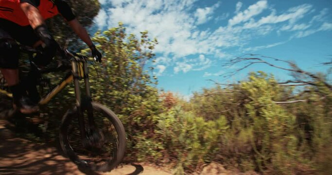 Extreme mountain biker riding over rough terrain steeply dowhill in slow motion