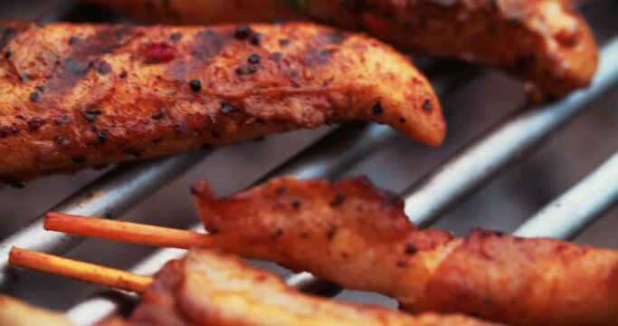 Overhead Shot Of A Crispy Skewered Chicken Wings Cooking On A Barbecue Grill Alongside Bacon Twists And Sliced Vegetables