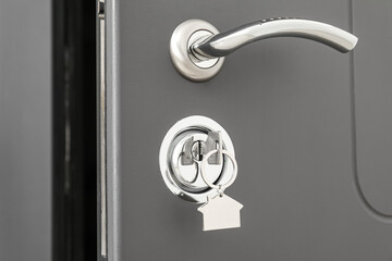 Key with silver keychain in door lock, closeup