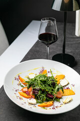 Delicious salad with figs arugula and goat cheese on white plate top view