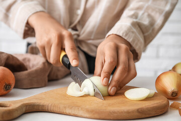 Obraz na płótnie Canvas Woman cutting fresh onion on table in kitchen, closeup