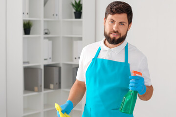 Male janitor with rag and detergent in office