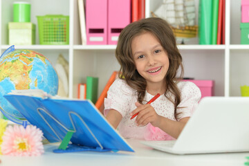 Cute little girl ding home work at desk