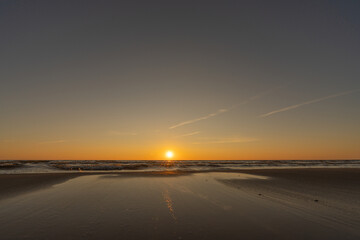 Sunset in a cloudless sky on the coast of the Gulf of Finland in Ust-Narva. The sky is clear, the waves gently roll on the sand. Estonia, Narva-Jyesuu. Natural background. Space for text.