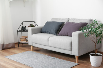 Grey sofa with cushions in interior of light living room