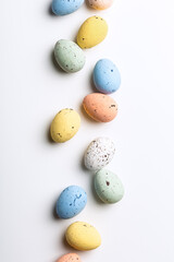 Naklejka na ściany i meble Easter composition of colorful quail eggs over white background. Springtime holidays concept with copy space. Top view