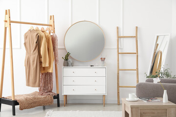 Interior of stylish makeup room with mirrors, clothes and drawers