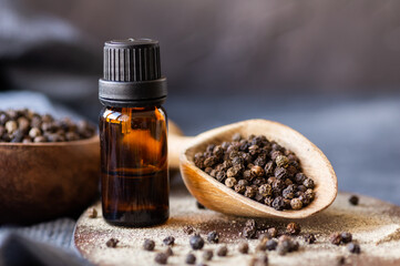 Glass Bottle of black pepper essential oil with peppercorns, alternative medicine