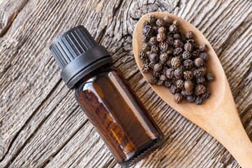 Obraz na płótnie Canvas Glass Bottle of black pepper essential oil with peppercorns, alternative medicine