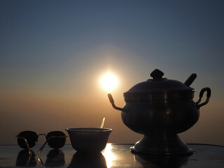 Silhouette of vintage soup pot with bowl and sunglasses on table