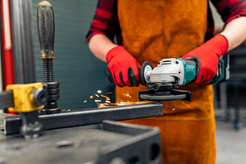A self-taught girl grinds in the workshop, uses a visor and gloves for protection