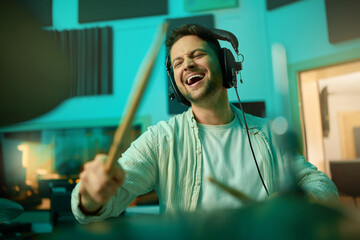 Musician, headphones and man drummer playing in a recording studio for production of a song....