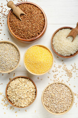Bowls with different cereals on white wooden background
