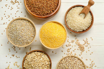 Bowls with different cereals on white wooden background