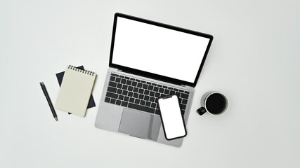 Above view laptop computer, smart phone, notepad and coffee cup on white background