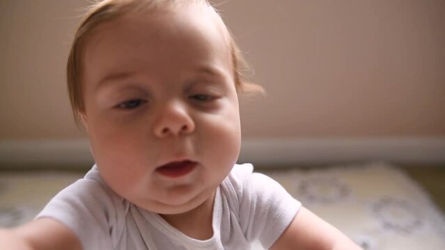 close up of baby's face while sitting and grabbing the camera