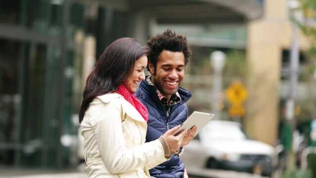 Medium shot couple using electronic tablet in city