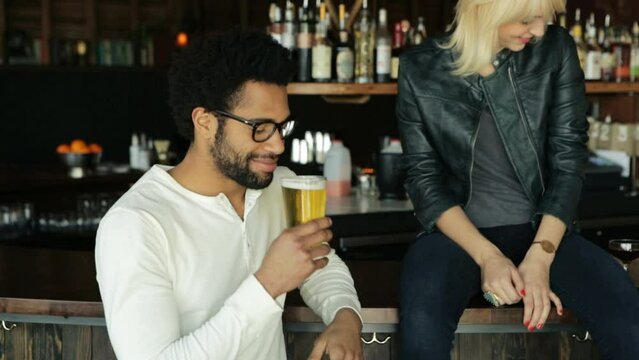 African american man with glasses receives a beer while a caucasian bl