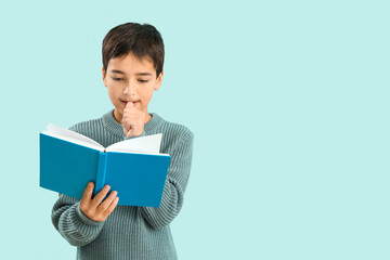 Obraz premium Little boy with book biting nails on blue background