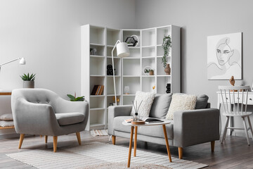 Cozy interior of living room with grey sofa, armchair and painting