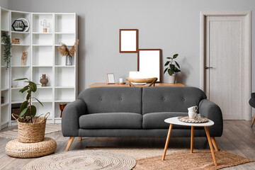 Stylish interior of living room with grey sofa, table and wicker pouf