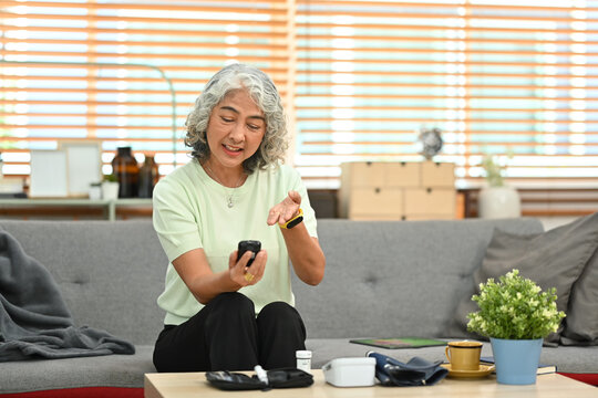 Diabetic Mature Woman Measuring Blood Glucose With Glucose Meter At Home. Diabetes And Elderly Health Are Concept