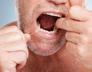 Hands, dental and mouth of man with floss in studio isolated on a gray background for health. Oral...