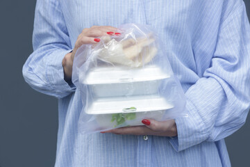 Woman's hands holding PVC plastic bag with takeaway foam lunch boxes. Single use food containers,...