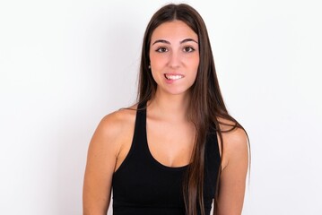 Fototapeta premium young woman wearing sportswear over white studio background being nervous and scared biting lips looking camera with impatient expression, pensive.