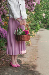 A basket with lilies of the valley and petunias in the hands.