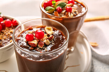 Plate with glasses and bowl of delicious chocolate pudding, cranberry and almond on white table