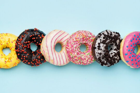Line made of different delicious donuts on blue background