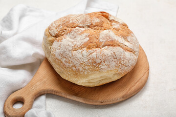 Cutting board with loaf of fresh bread on white table