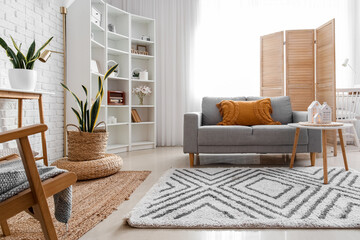 Interior of living room with sofa and glowing house candle holders on table