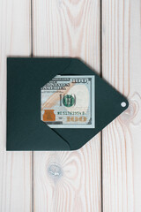Flat lay of open green emerald envelope with one hundred dollars inside on grey wooden table. Correspondence, money.