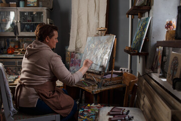 Fototapeta na wymiar a female artist is engaged in painting in a creative studio