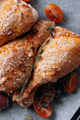 chicken drumsticks with spices, paprika and sesame seeds, ready to bake on a baking sheet