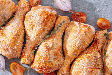 chicken drumsticks with spices, paprika and sesame seeds, ready to bake on a baking sheet