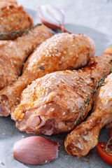 chicken drumsticks with spices, paprika and sesame seeds, ready to bake on a baking sheet
