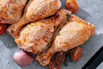 chicken drumsticks with spices, paprika and sesame seeds, ready to bake on a baking sheet