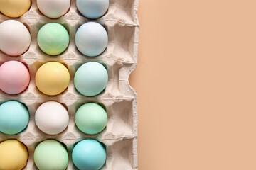 Cardboard holder with beautiful Easter eggs on color background, closeup