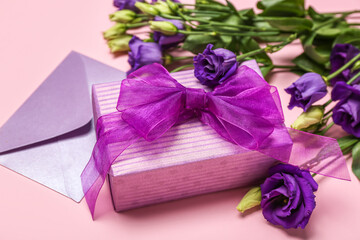 Beautiful eustoma flowers, envelope and gift for Women's Day celebration on pink background