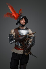 Portrait of medieval conquistador dressed in plate armour holding epee.