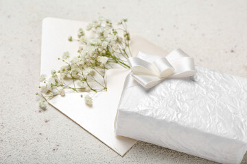Fototapeta na wymiar Beautiful gypsophila flowers, envelope and gift for Women's Day celebration on grey background