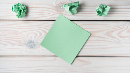 Flat lay of blank green sticker sticky note near crumpled notes on grey wooden table. Search, no...