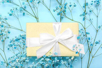 Beautiful gypsophila flowers and gift for Women's Day celebration on blue background